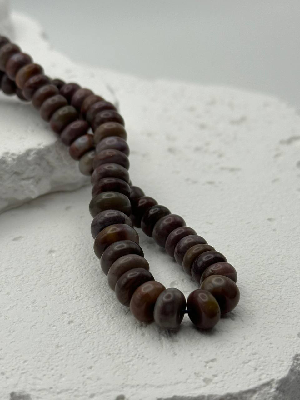 Brown and green beads on a textured white surface
