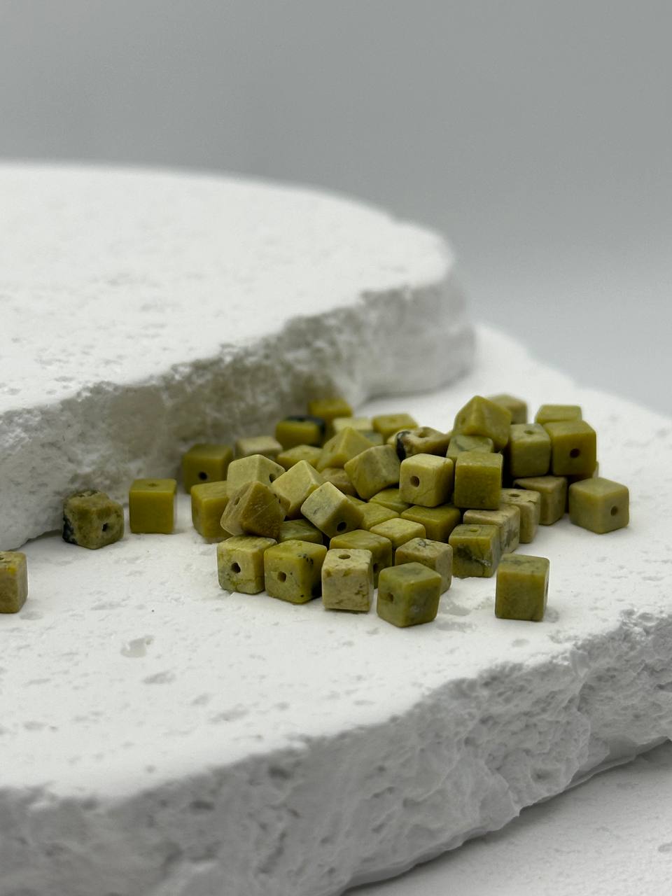 Small green cubes on a textured white surface with a gray background