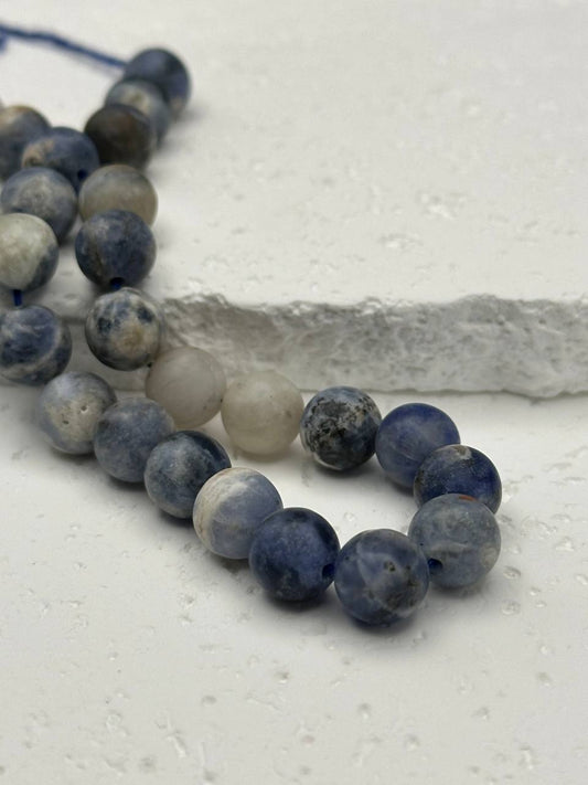 String of blue and gray beads on a textured white surface