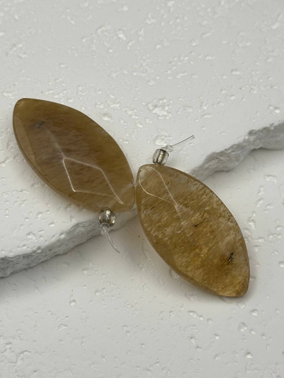 Pair of leaf-shaped beads on a textured white surface