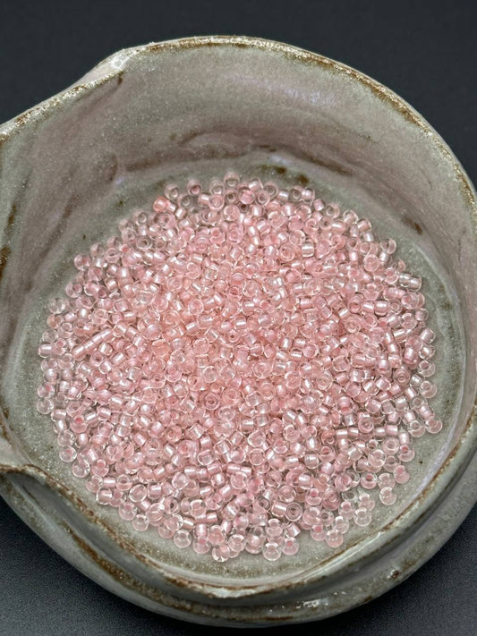 small container filled with rose colored beads