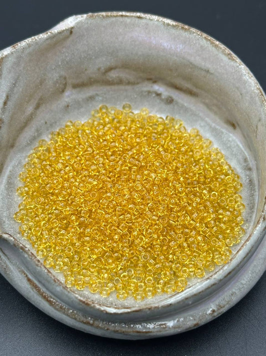 Close-up of yellow beads in a ceramic container on a dark background