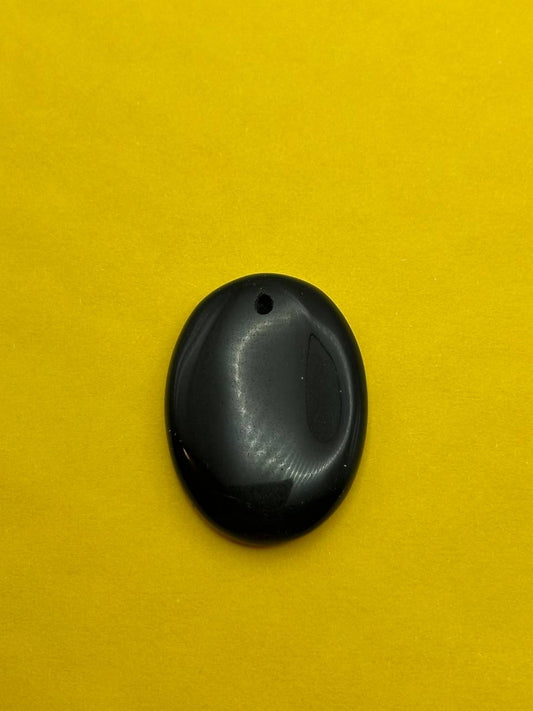 Black agate pendant on a yellow background