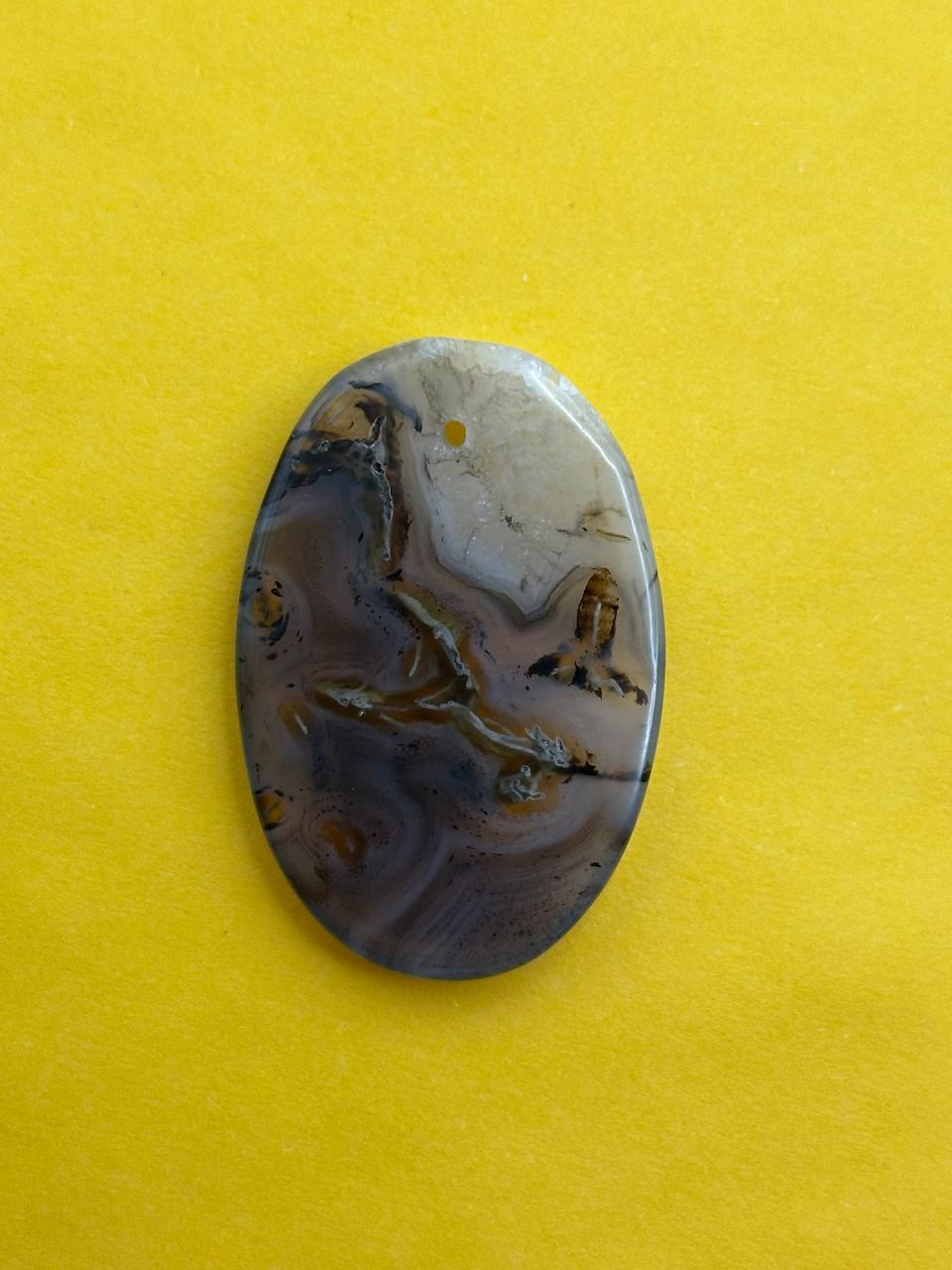 Oval-shaped stone with marbled pattern on a yellow background