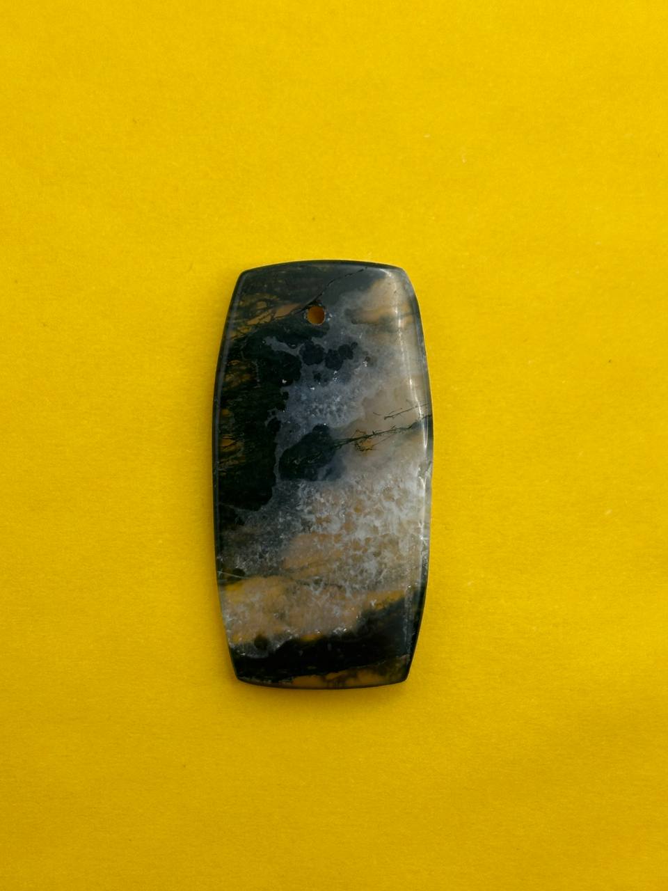 Rectangular stone with black and gray patterns on a yellow background