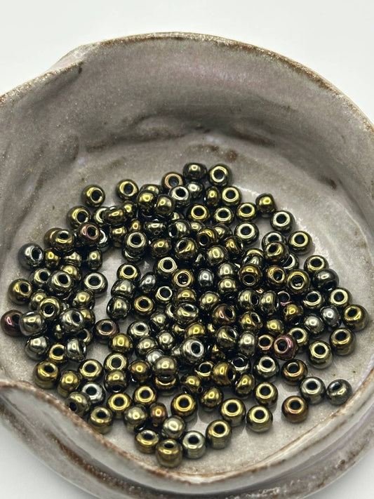 Small metallic beads in a ceramic dish on a white background