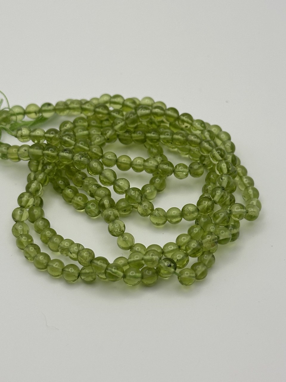 Transparent round peridot beads on white surface