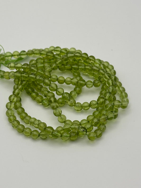 Transparent round peridot beads on white surface