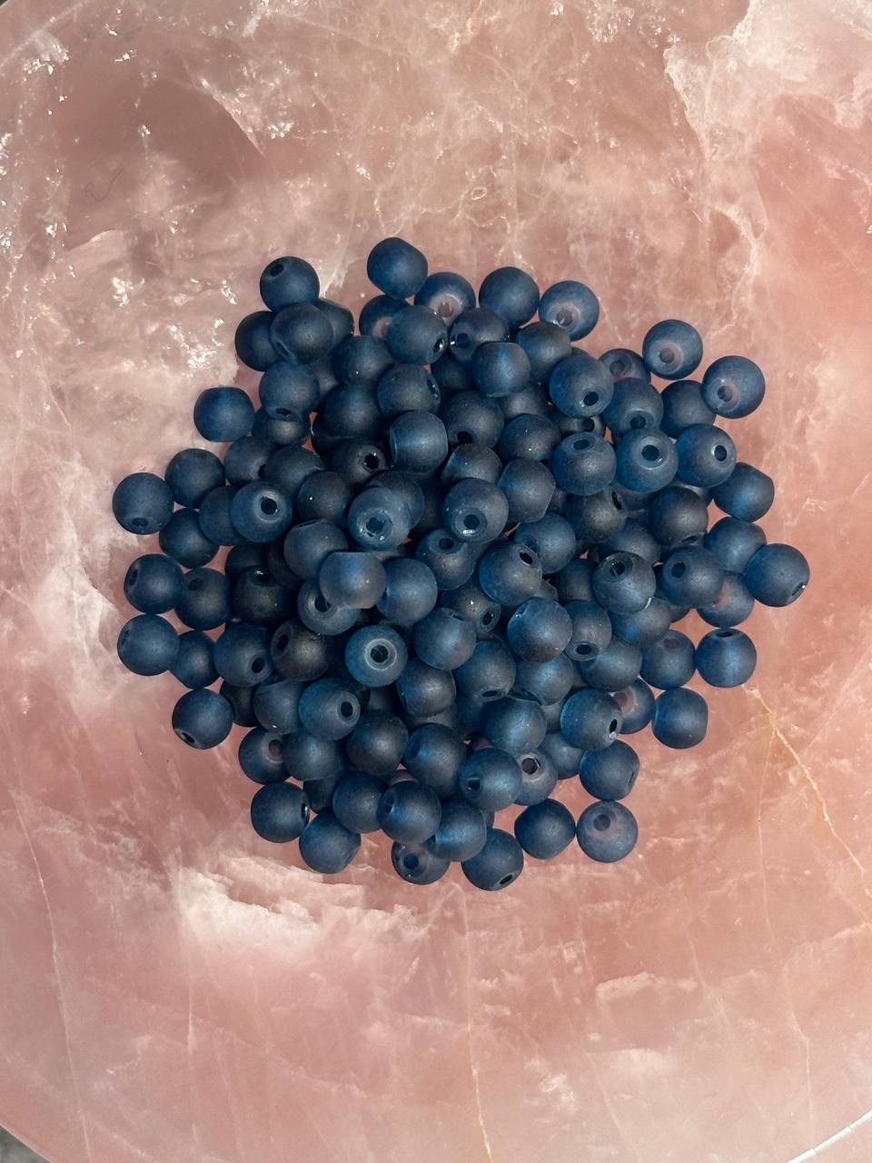 Dark teal beads on a pink marble surface