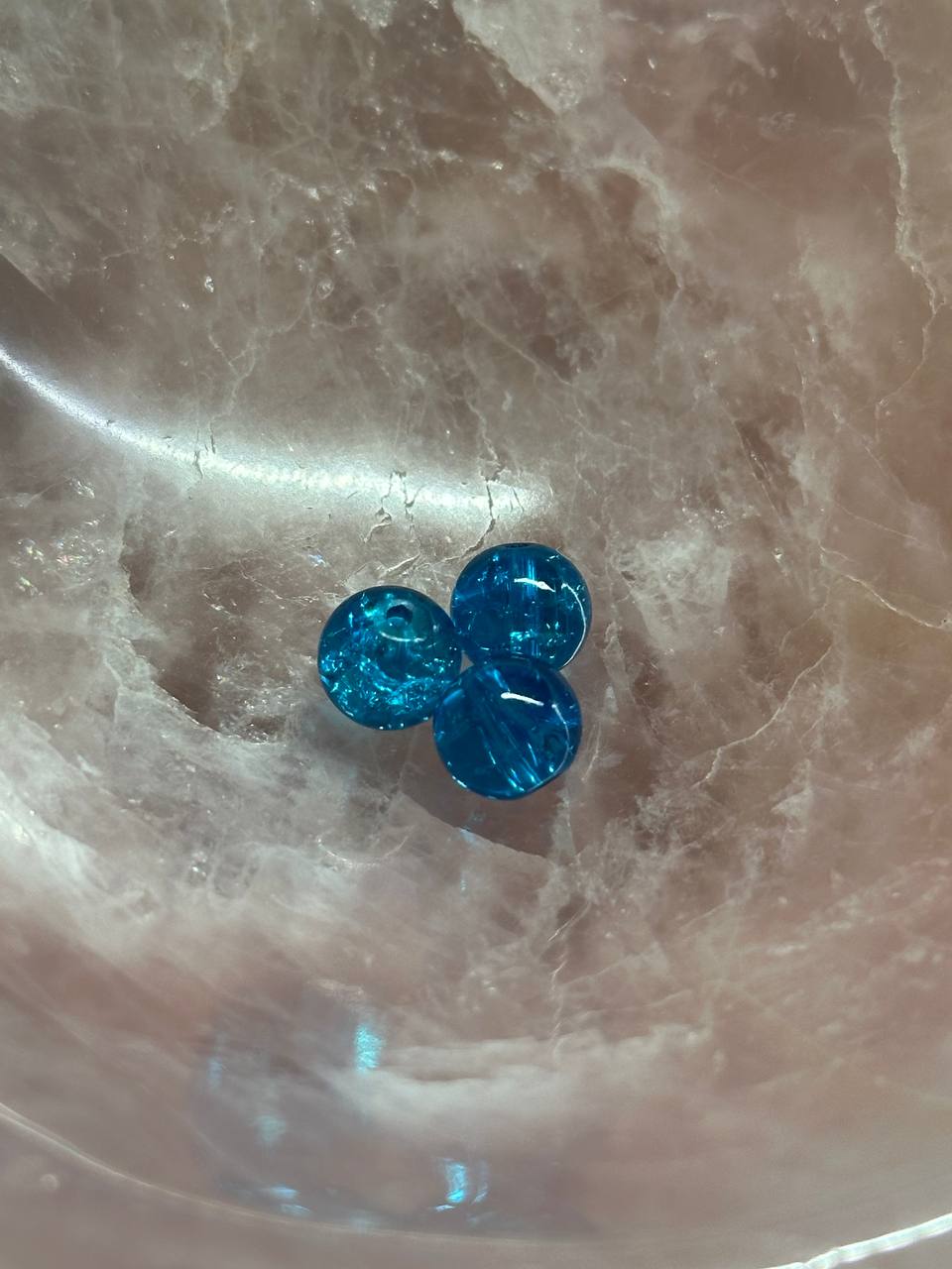 Three blue marbles on a marble surface