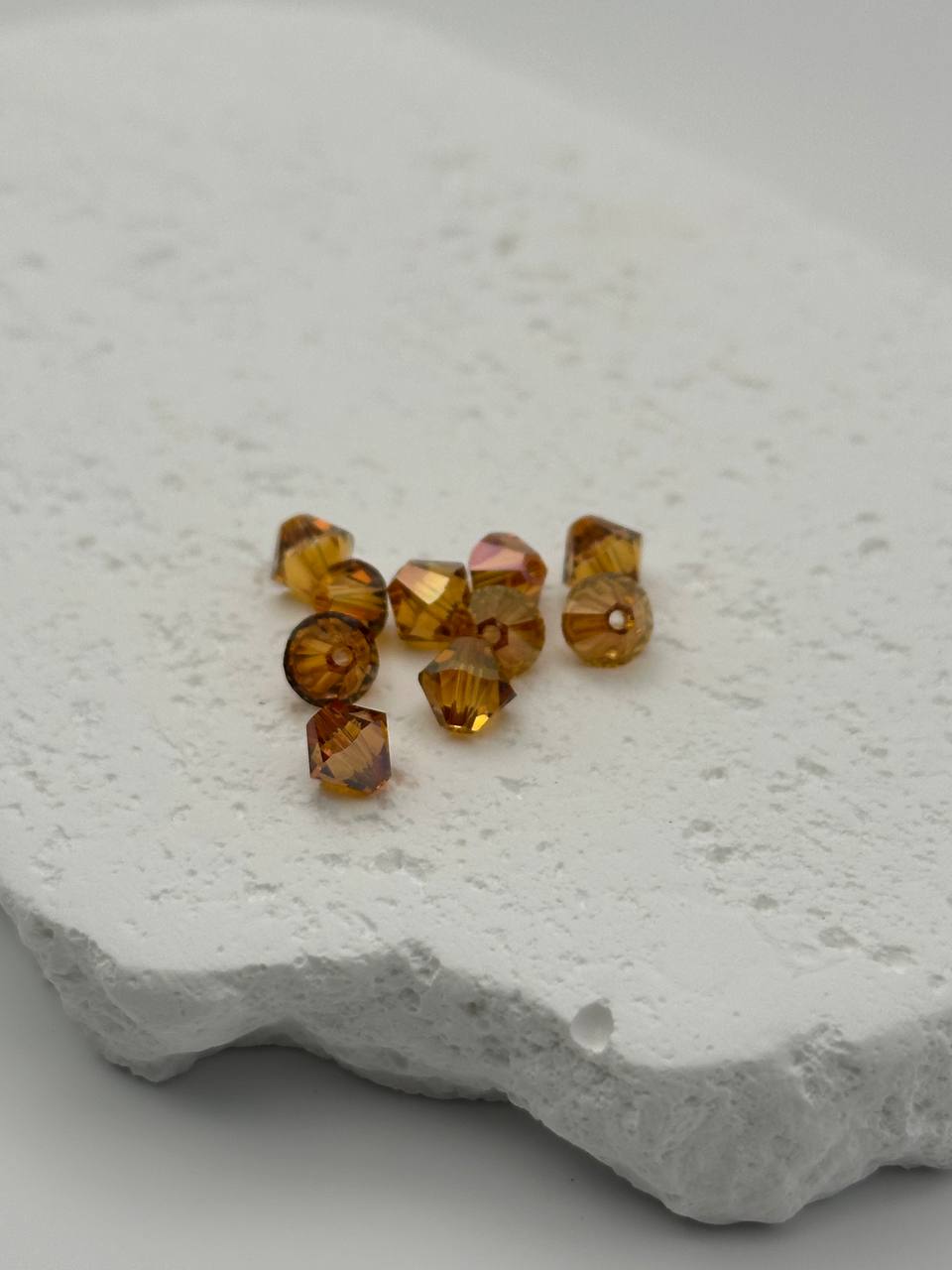 Copper bicone beads on a textured white surface