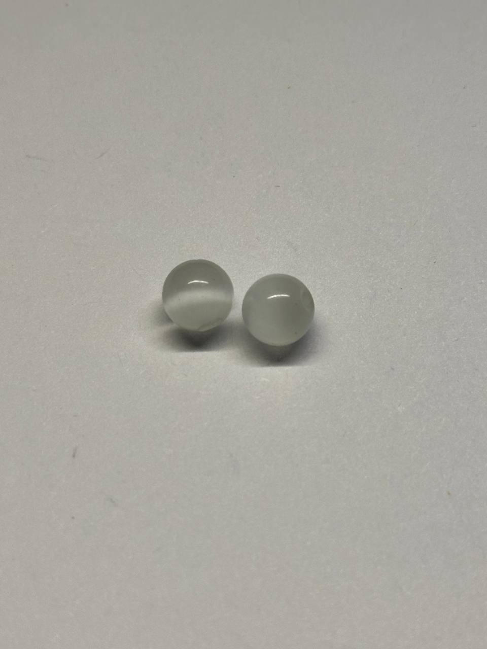 Two small round cat eye beads on a light gray background