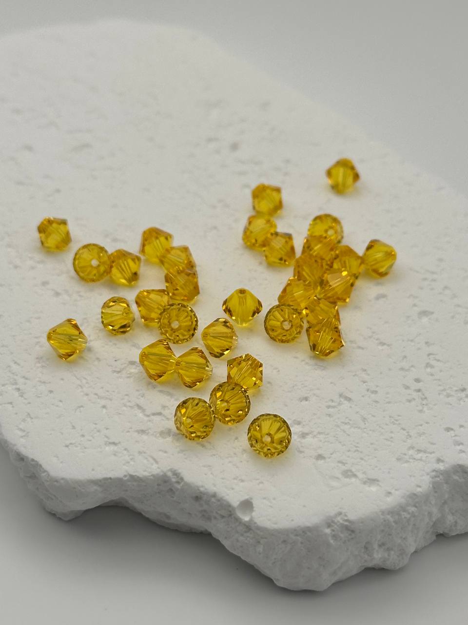 Yellow bicone beads on a textured white surface