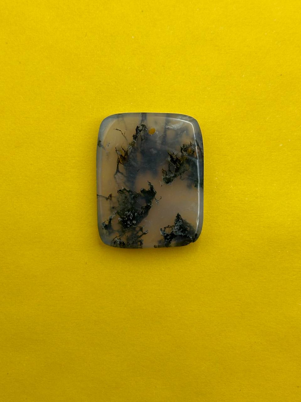 Rectangular stone with black and gray patterns on a yellow background