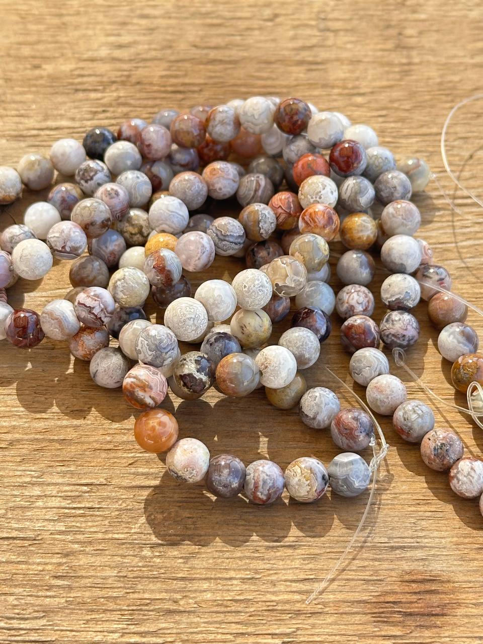 String of multicolored crazy lace agate beads on a wooden surface