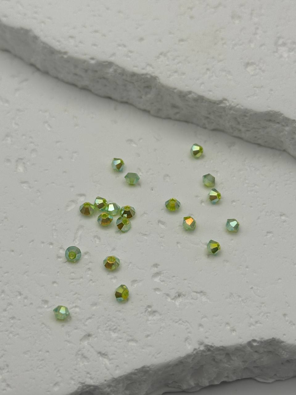 Small green gemstones on a textured white surface