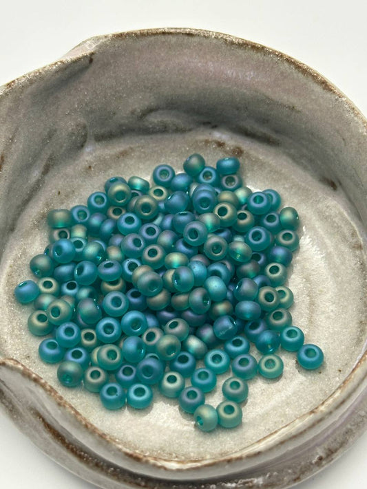 Small pile of blue beads in a ceramic container