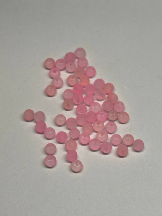 Pink beads scattered on a light gray background