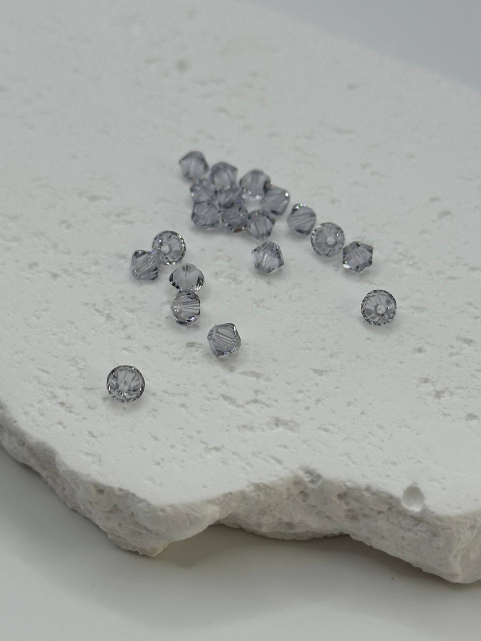 Smoky mauve bicone beads on a textured stone surface