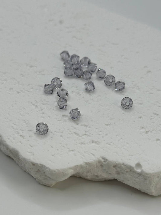 Smoky mauve bicone beads on a textured stone surface