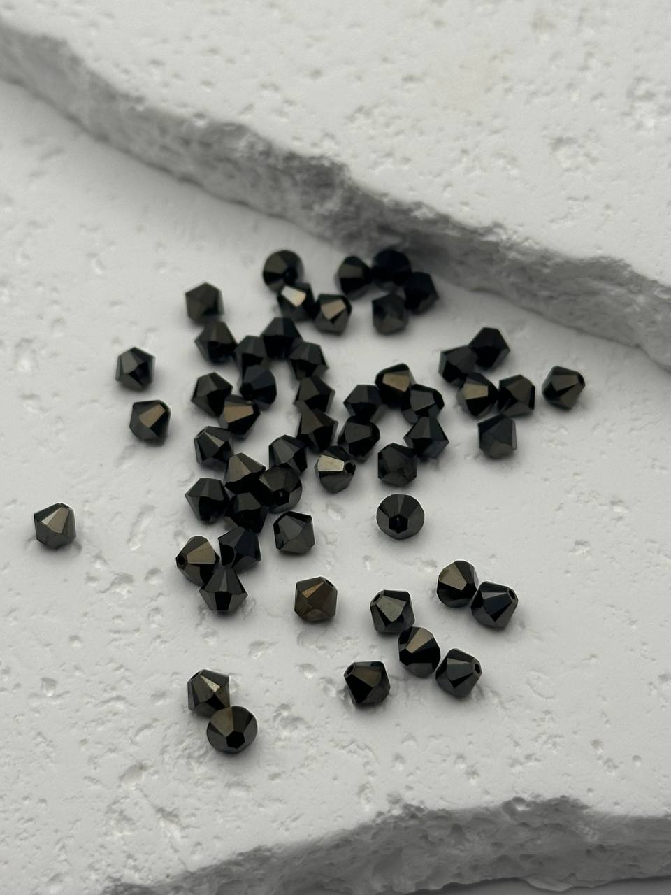 Black bicone beads on a light gray surface
