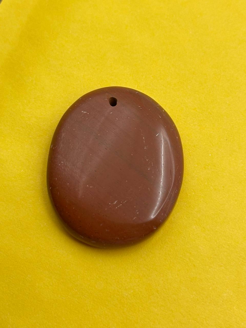 Brown oval stone with a hole on a yellow background