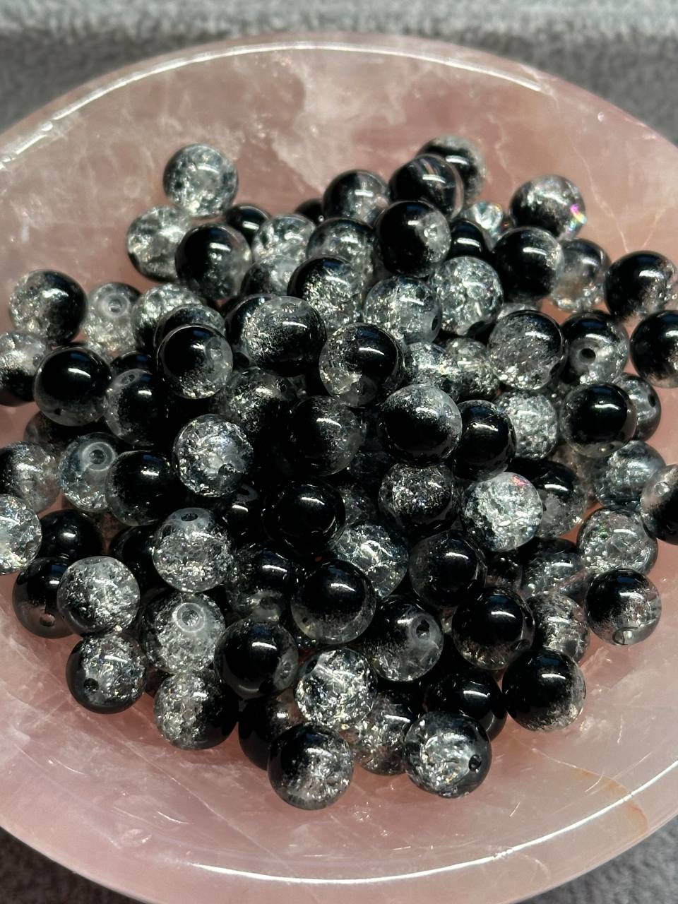 Black and silver glittery beads on a pink stone surface