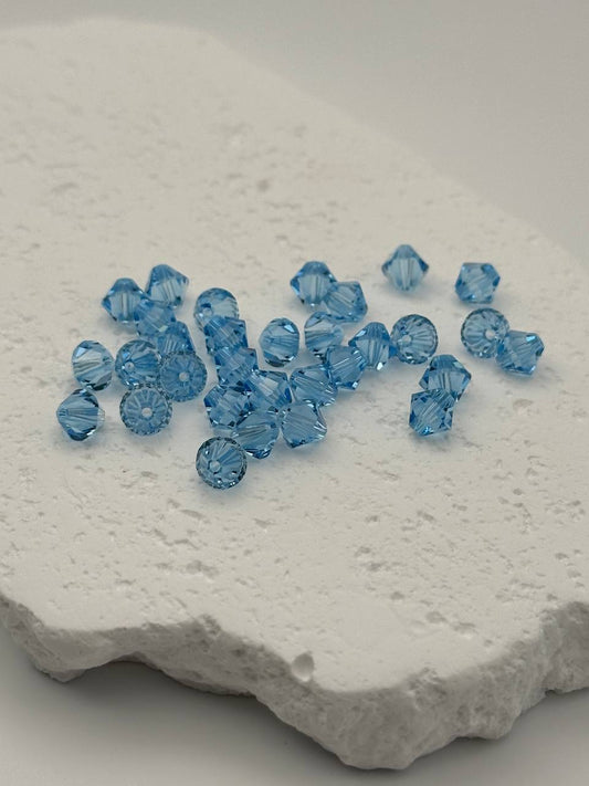 Aquamarine bicone beads on a textured white surface