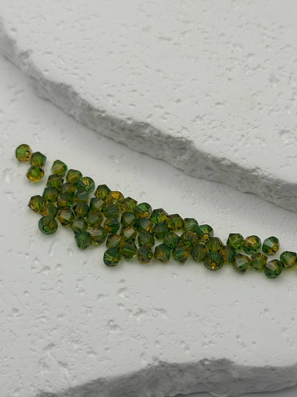 Green bicone beads on a textured white surface