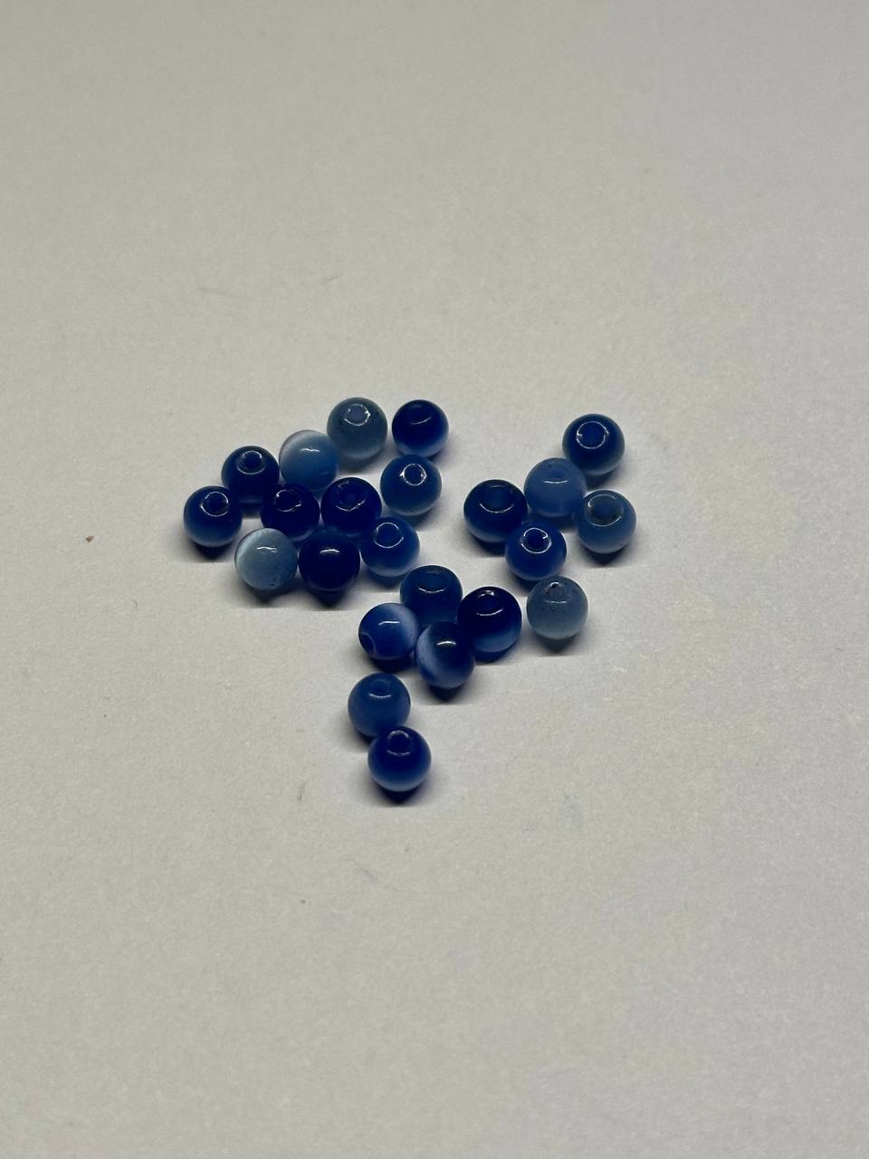 Blue cat eye beads scattered on a white surface
