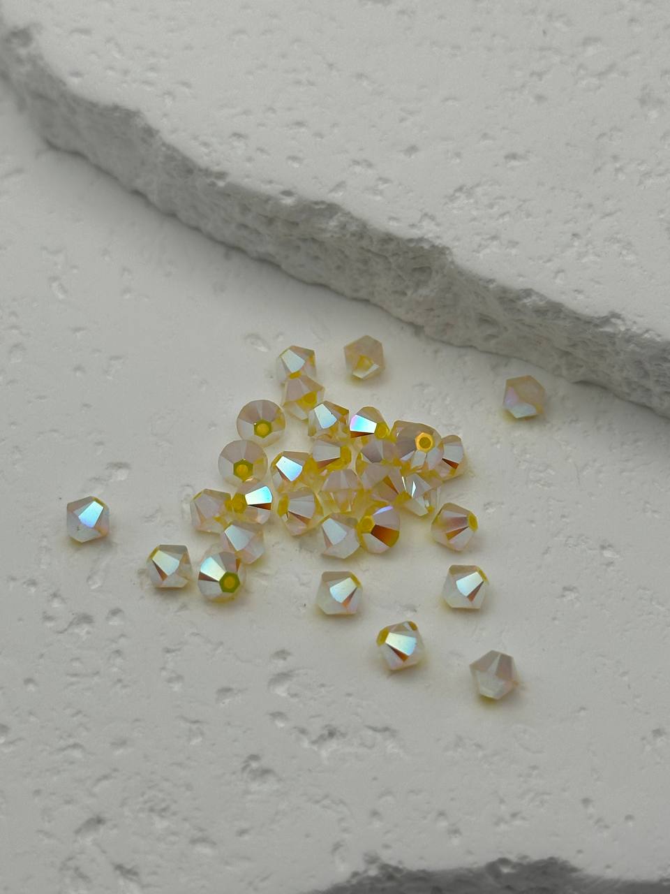 closeup of yellow bicone beads on grey surface
