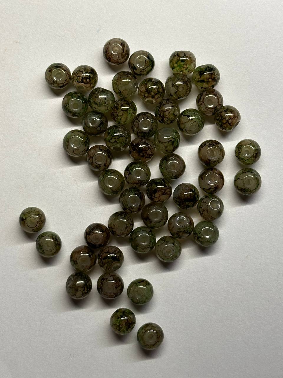 Green picasso beads scattered on a white background