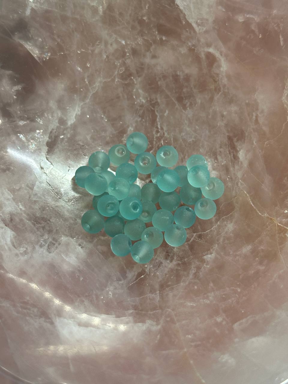 Teal beads on a textured beige surface