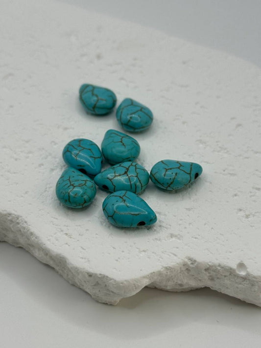Turquoise teardrop beads on white surface