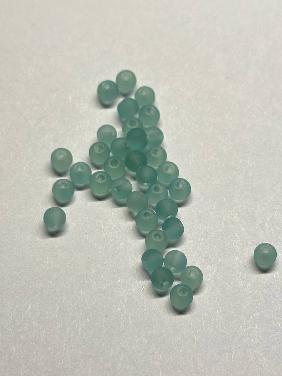 Teal beads scattered on a white surface