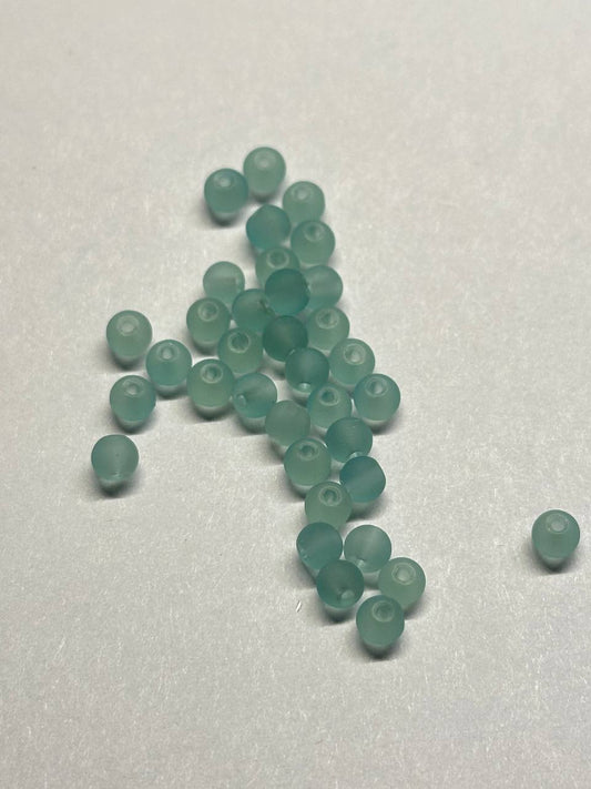 Teal beads scattered on a white surface
