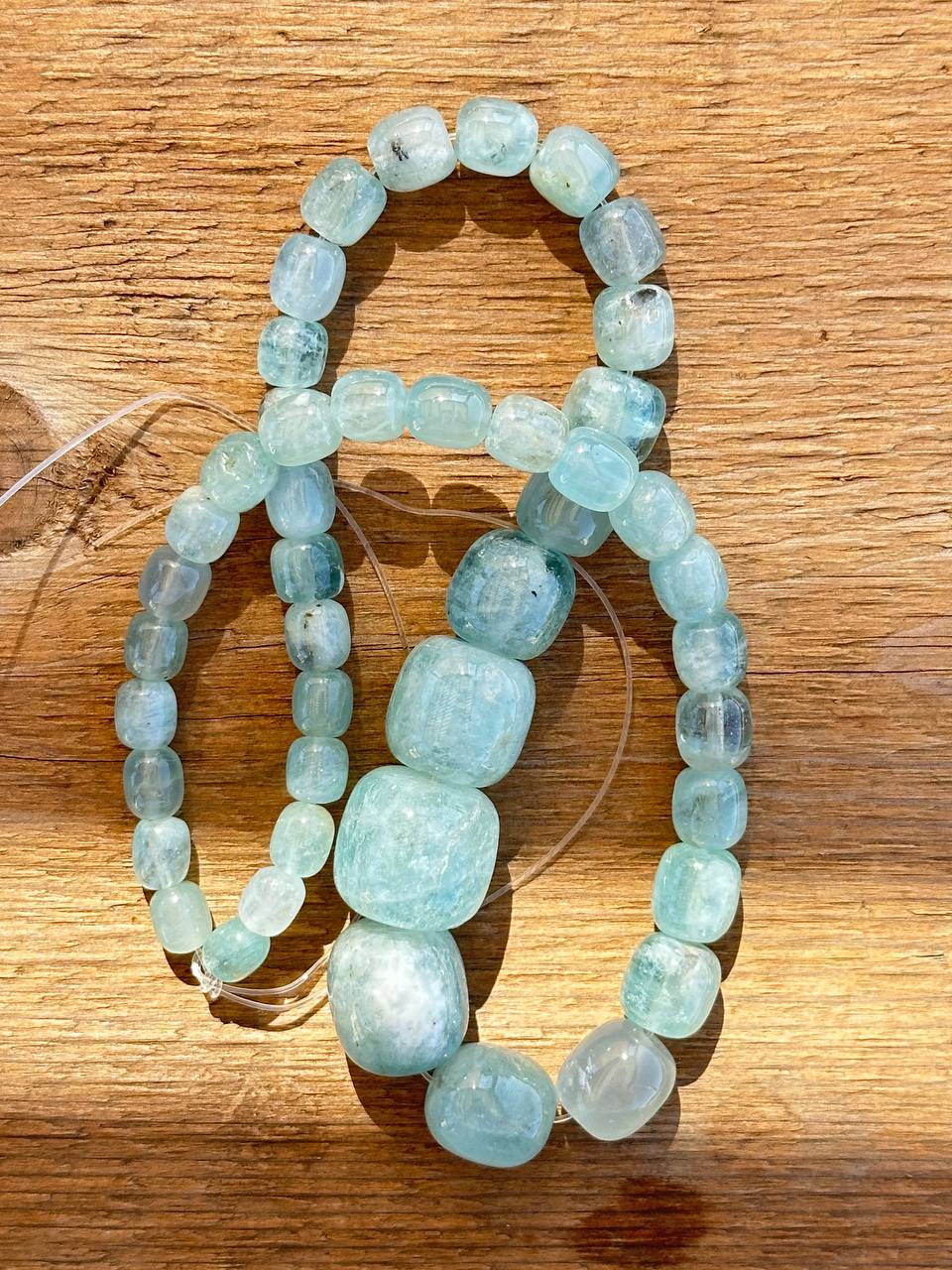 Set of light blue aquamarine beads on a wooden surface