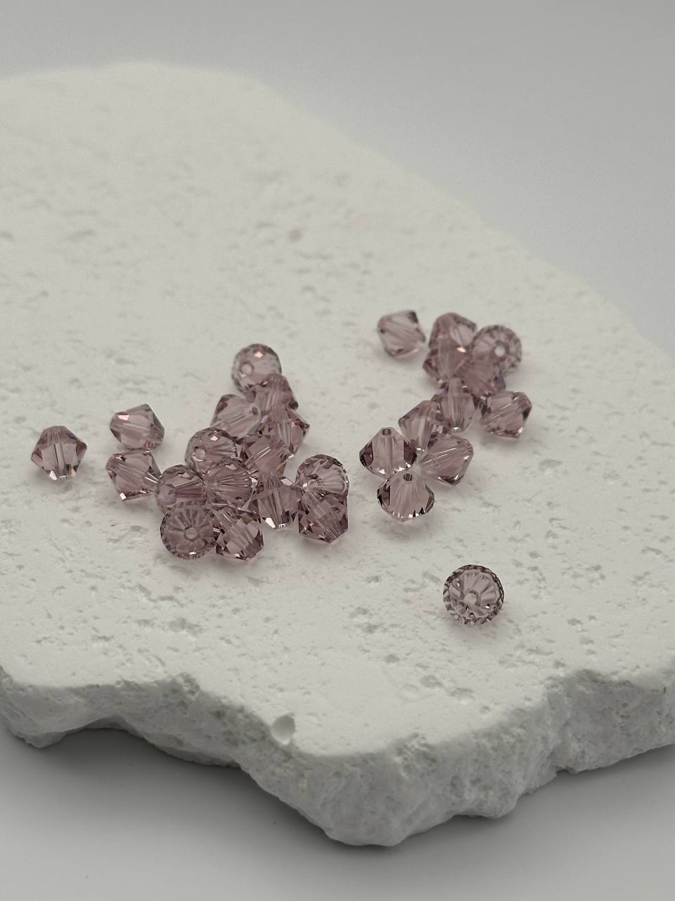 Light amethyst bicone beads on white surface