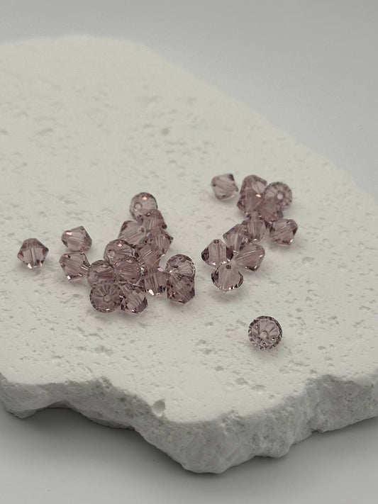 Light amethyst bicone beads on white surface