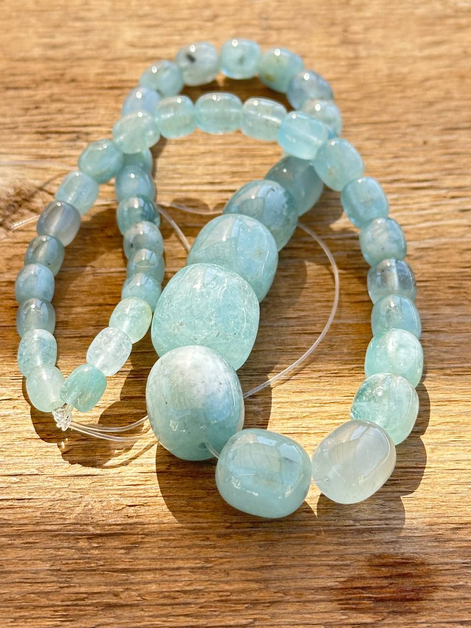 Light blue aquamarine graduated beads on wooden surface