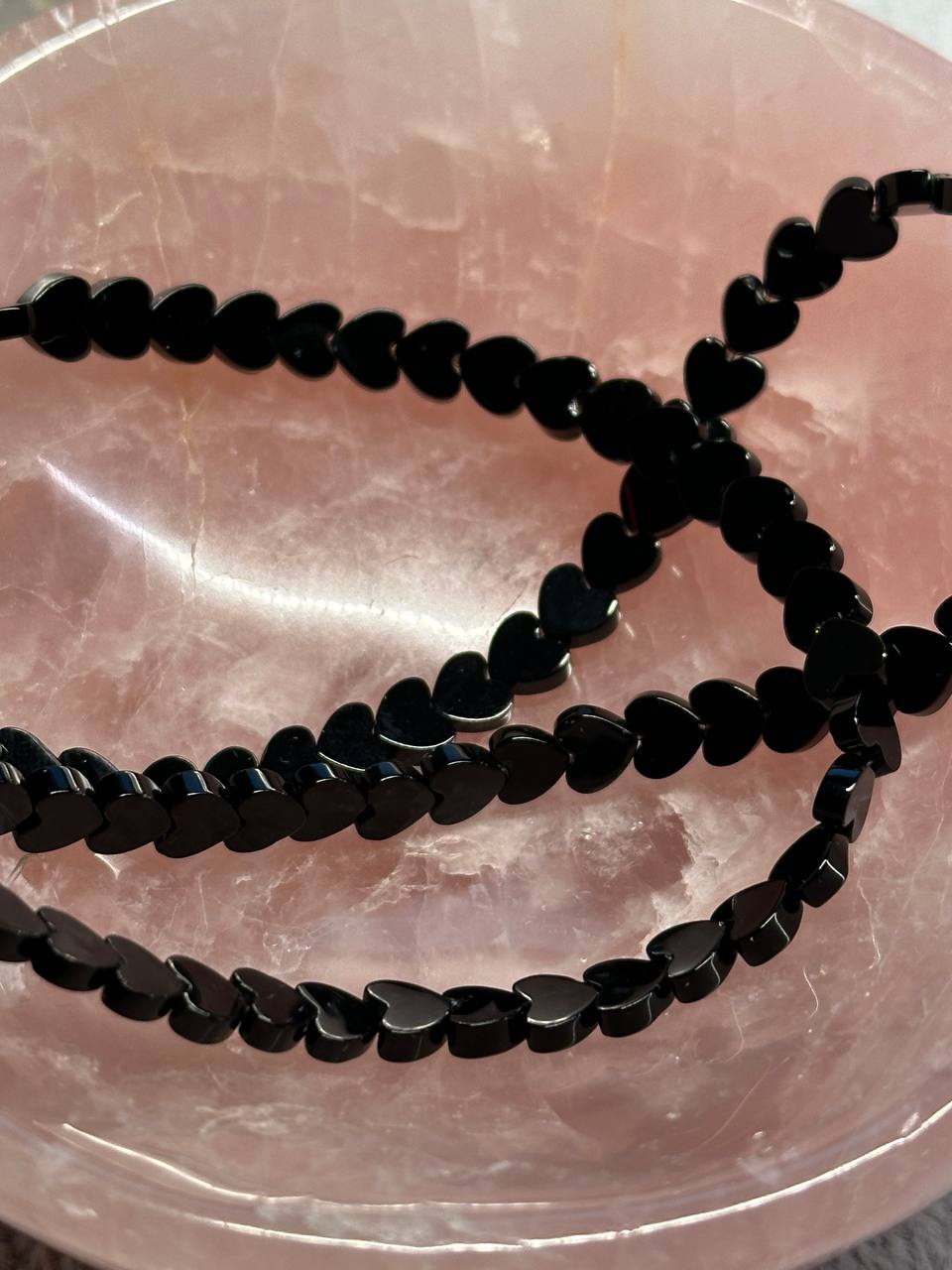 Black heart-shaped beads on a pinkish surface
