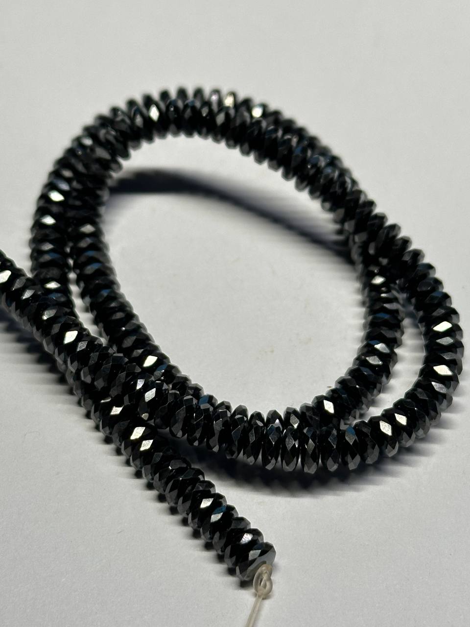 Black hemalyke faceted beads on a light gray background