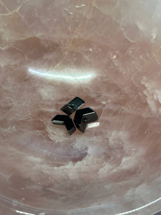 Black chevron hemalyke or hematite beads on a pink marble surface