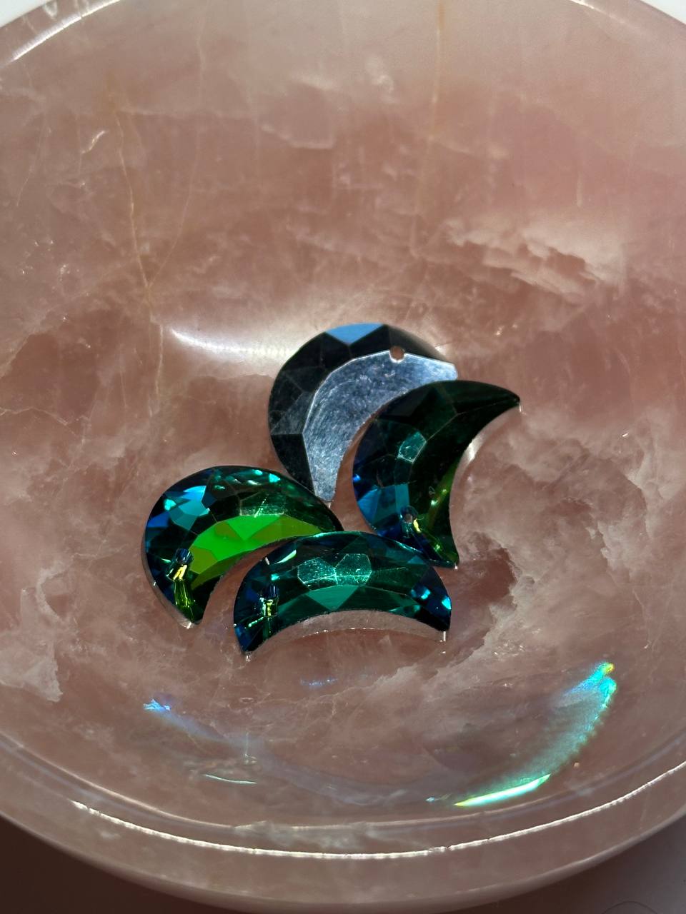 Multicolored moon-shaped bead on a pink stone surface