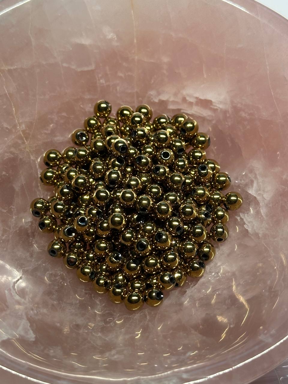 Gold beads on a pinkish surface