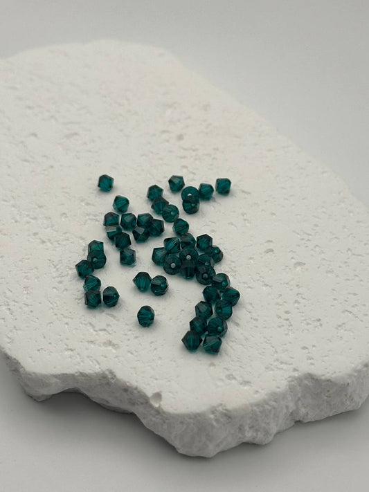 Emerald bicone beads on a textured white surface