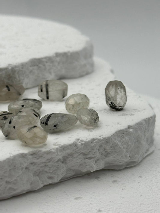 Tourmalinated quartz beads on white surface