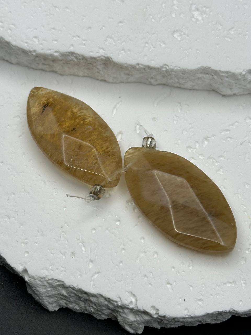 Pair of leaf-shaped beads on a textured white surface