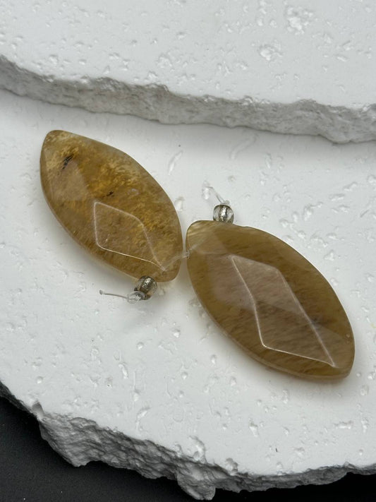 Pair of leaf-shaped beads on a textured white surface