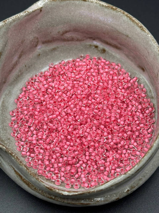 Small container filled with pink beads on a dark background